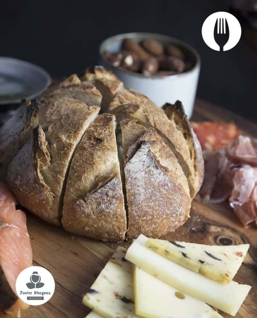 Bolletje van zuurdesembrood op een plank met kaas en worst, dat wordt aangeboden op Proef Amersfoort