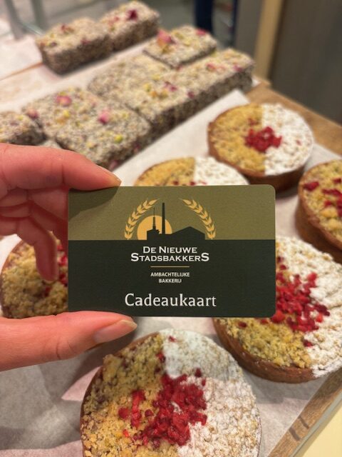 Een cadeaukaart van De Nieuwe Stadsbakkers bakkerij in Amersfoort, vastgehouden voor het taart assortiment.